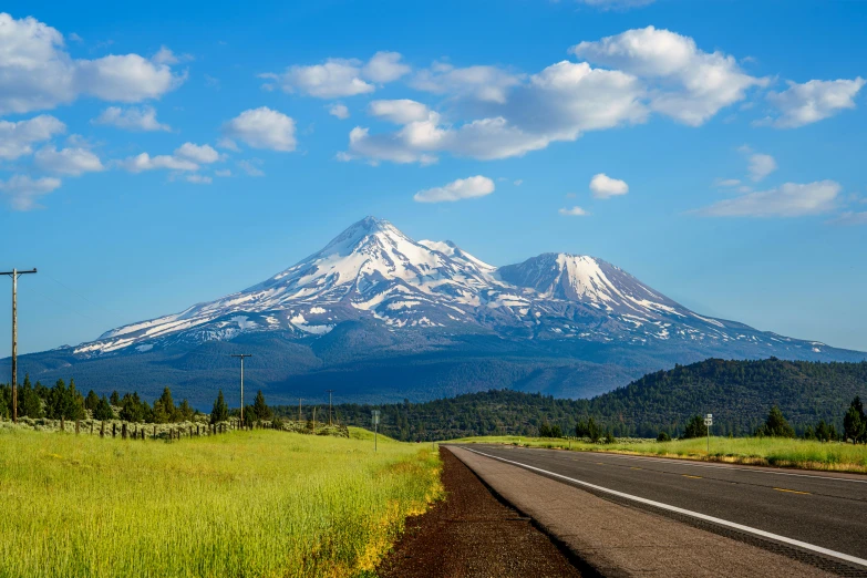 the mountain is very tall and it looks like it is in the middle of the road