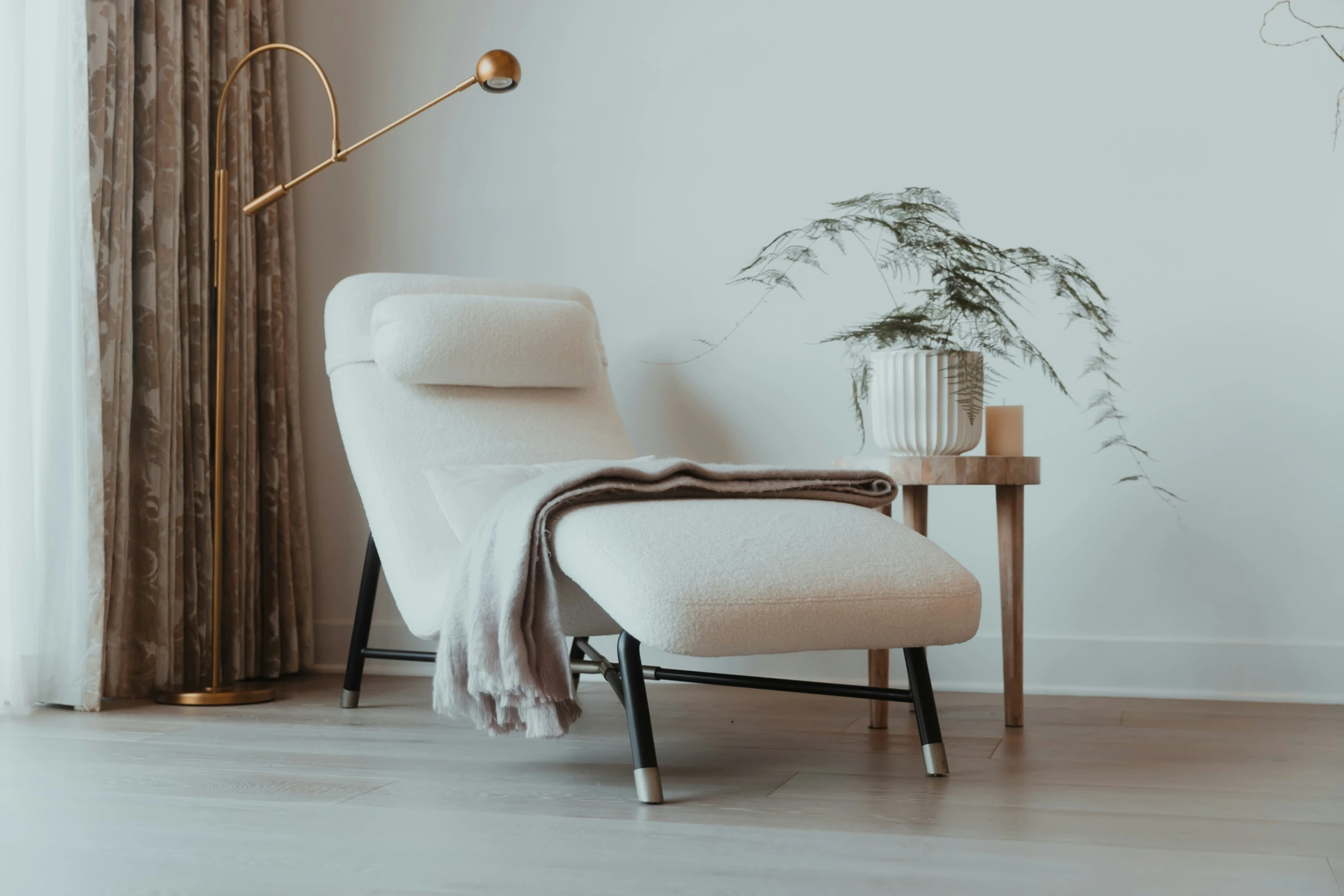 a room with white furniture, plants and a lamp