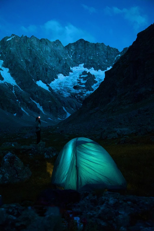 a tent in the mountains lit up by flashlight