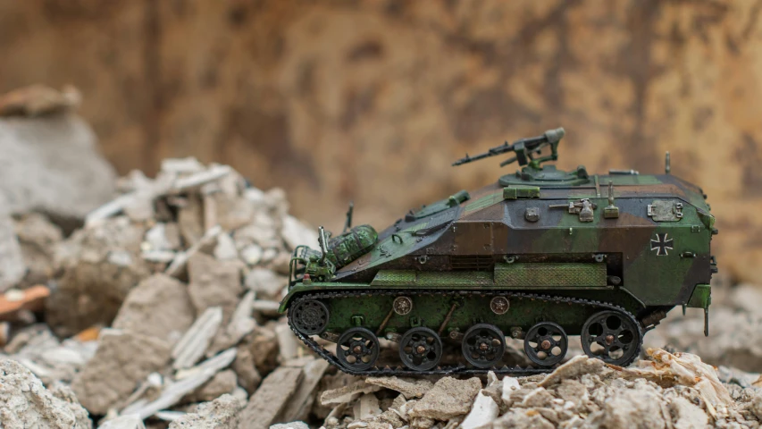 a toy army tank and its surroundings in a pile of rocks