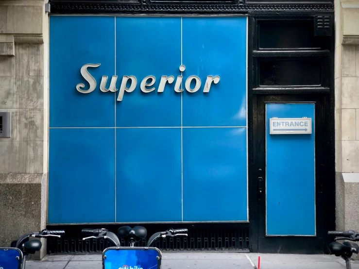 two mopeds parked in front of a building with the word superior on it