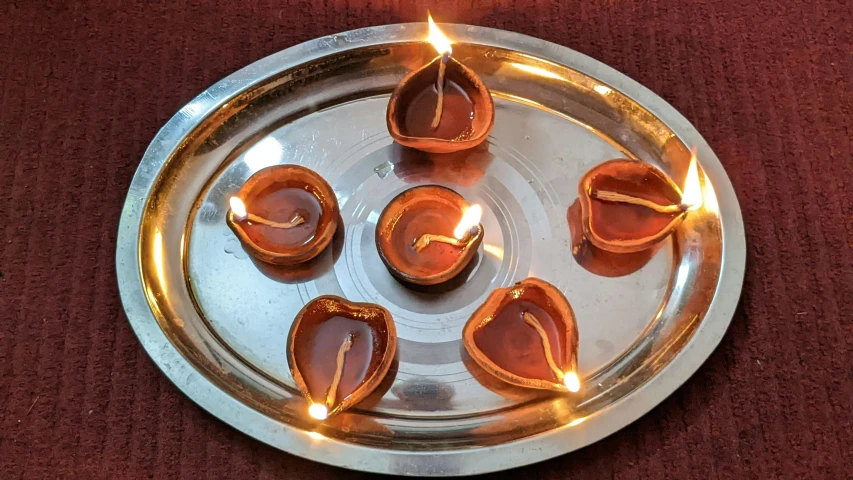 an arrangement of five candles placed on a metal plate