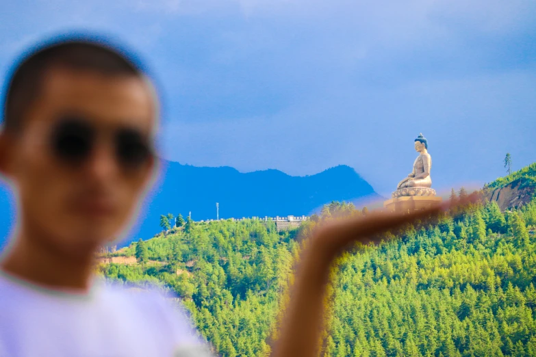 a woman standing in front of a mountain with trees