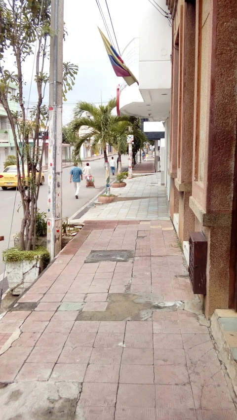 a narrow city sidewalk with flags and a street light