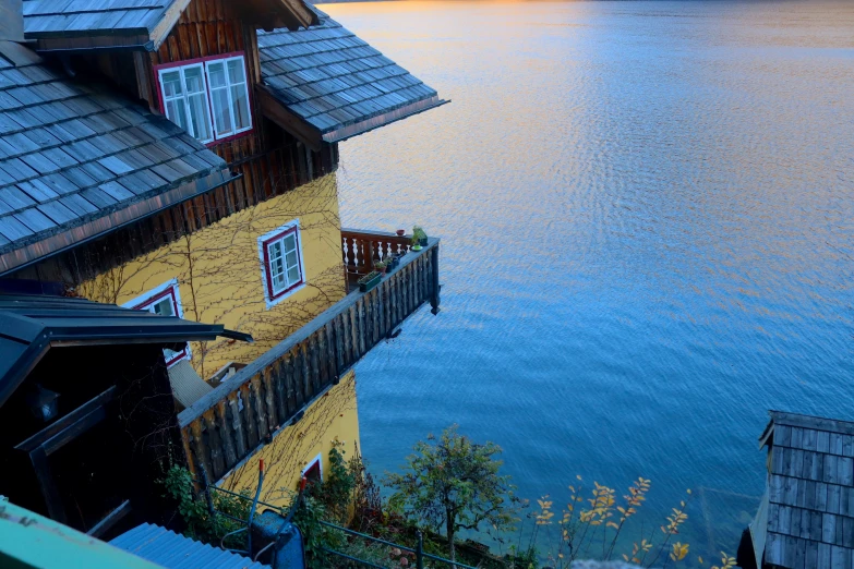 a small house sitting next to a lake with a wooden balcony