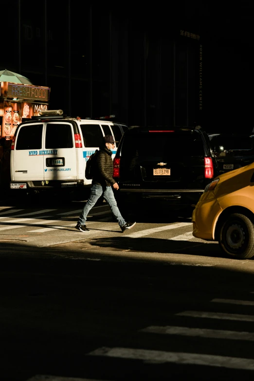 a man crossing the street at night with a skateboard