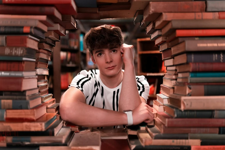 a male in a white shirt and books stacked up