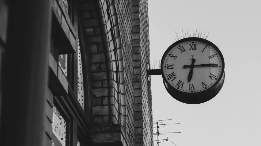 an outdoor clock is posted on the side of a building