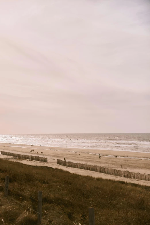 two people walking on a boardwalk next to the beach