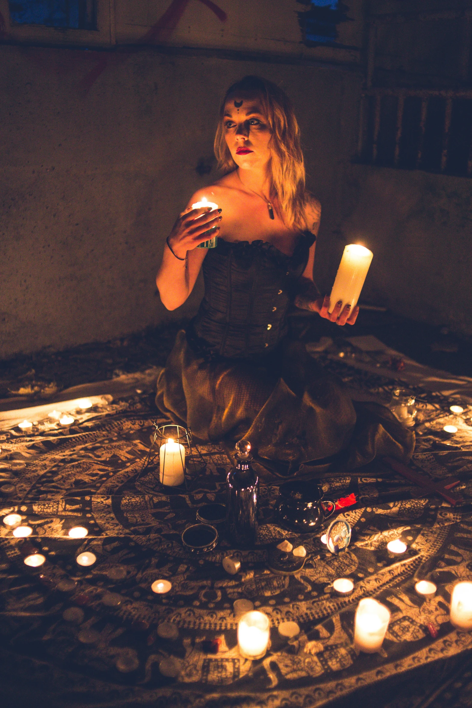 a woman kneeling down with a candle in her hand