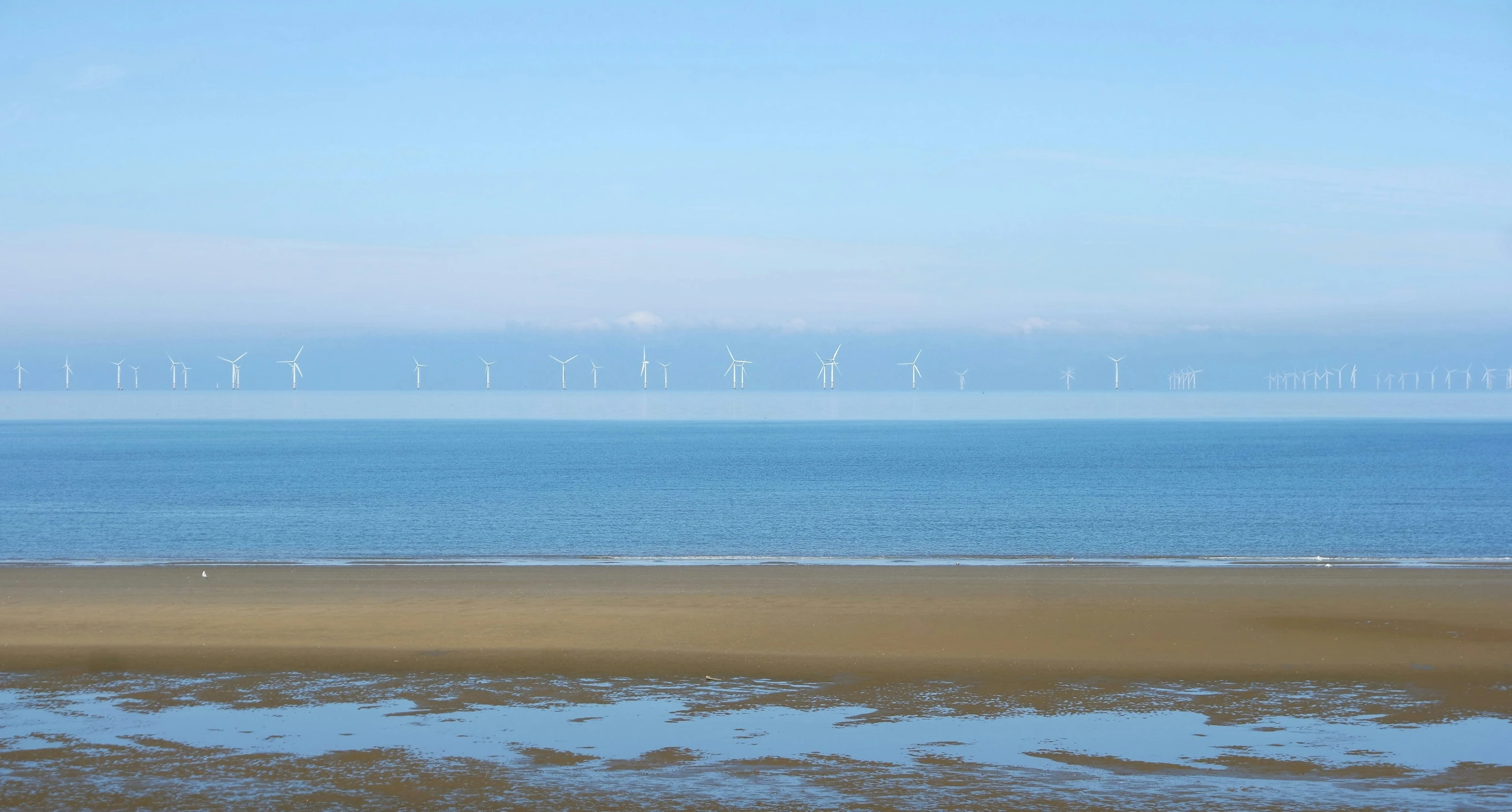 an open ocean sits empty, but blue skies are seen