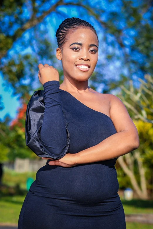 a beautiful woman standing in a park wearing a black dress