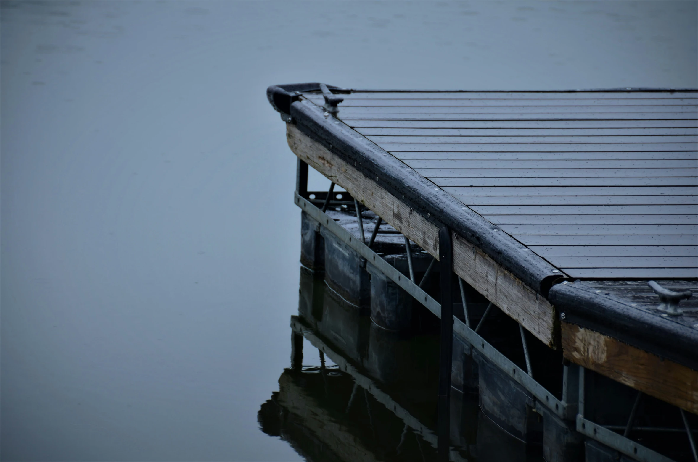 two birds perched on a dock that is over water