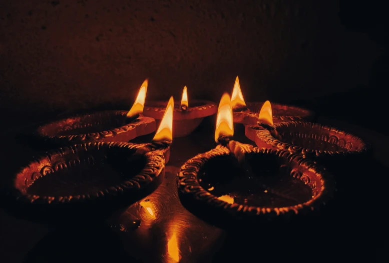 a group of candles lit in the dark with no one around them