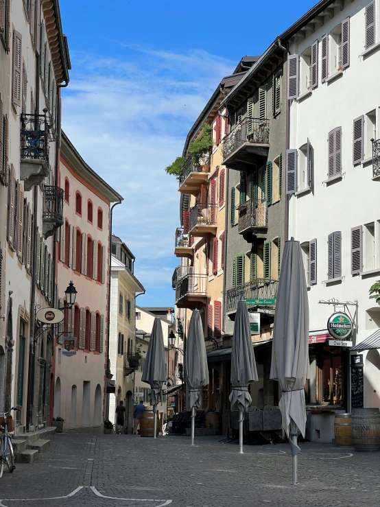 several buildings with open umbrellas and street cafe tables