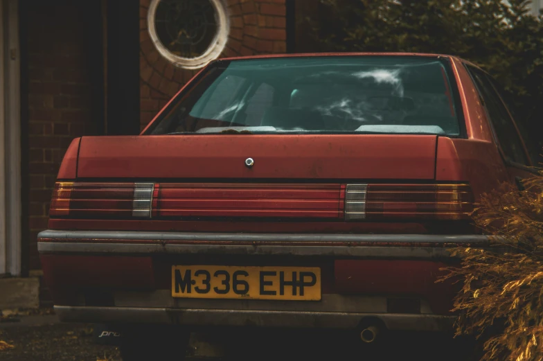 an old red car parked outside of a building