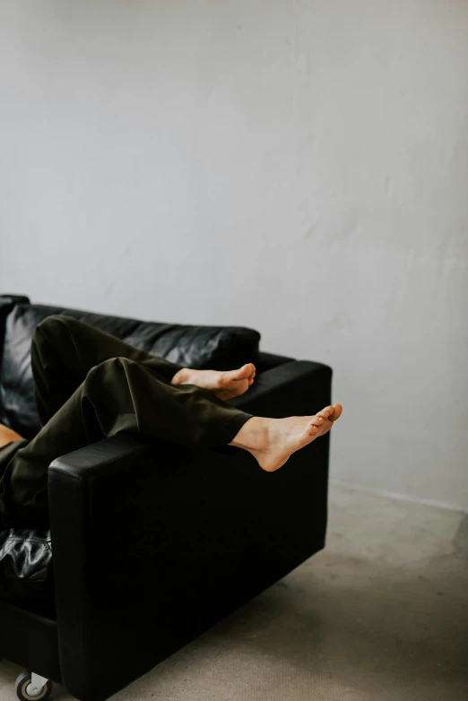 a man laying on a couch wearing an green jacket