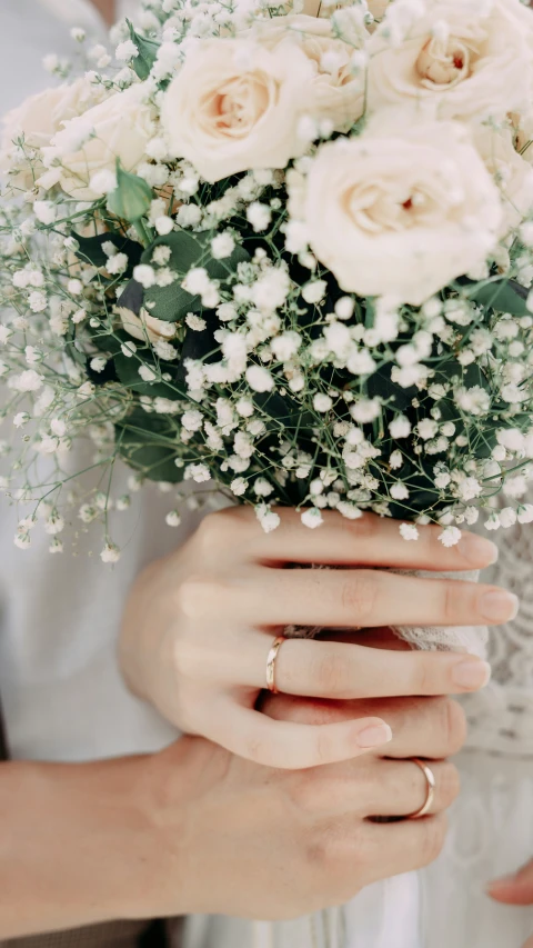 someone holding up some white flowers on their hands