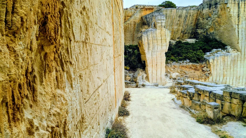 a walk way near large rocks leading to a cave