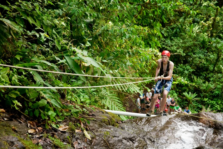 a man walking across a river while holding onto a rope