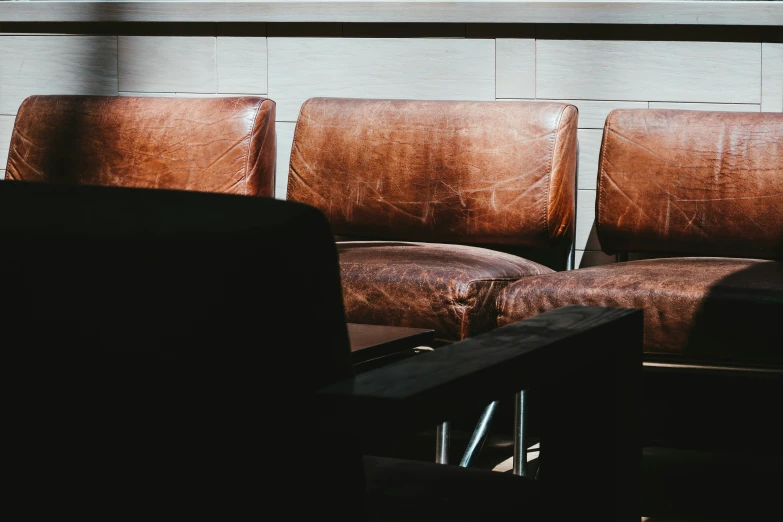 brown leather seats line up against the wall in an empty room