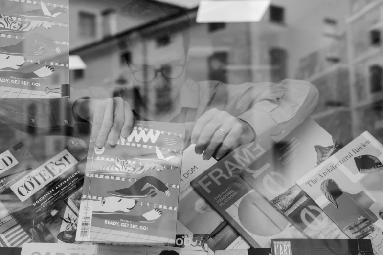 black and white po of a window display with a woman putting newspapers inside of it