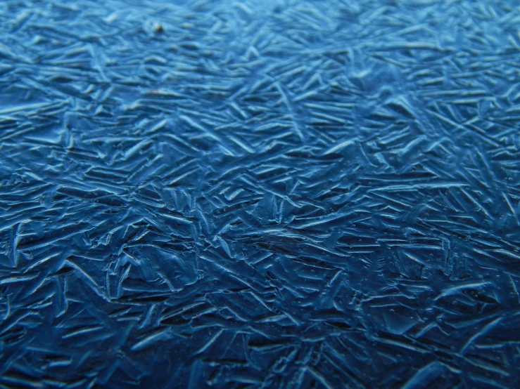 a blue frosty glass window with small drops of ice on the side