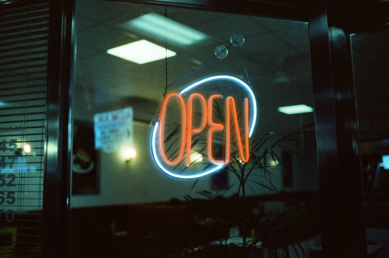 a neon sign behind the window of a closed restaurant