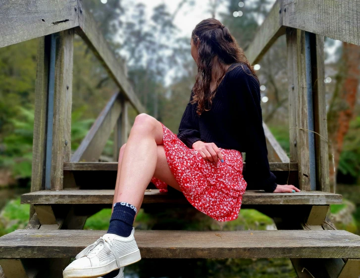 the woman in the skirt sits on the bench