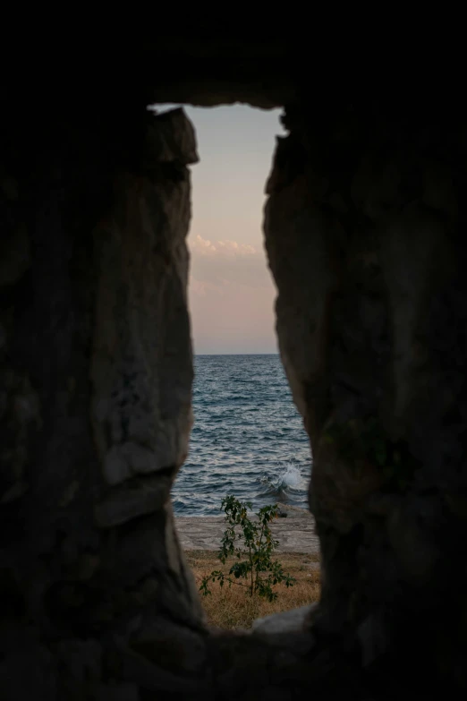 view out a window at an ocean with some rocks