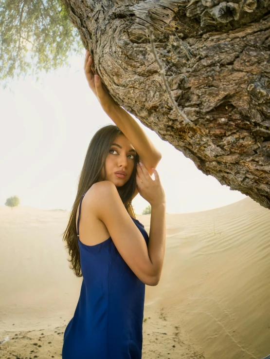 a woman standing under a tree next to a desert