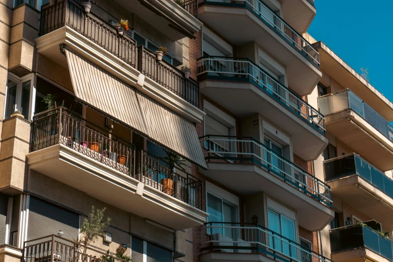 the balconys of a multi - story building are painted tan