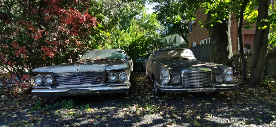 two old cars parked on a gravel road