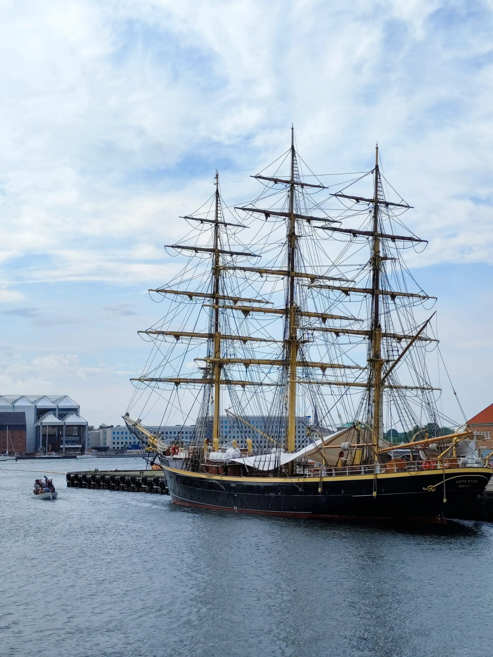 a large sailing ship docked in front of a shore town