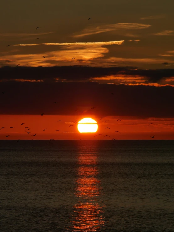 the sun is setting on the horizon in the water