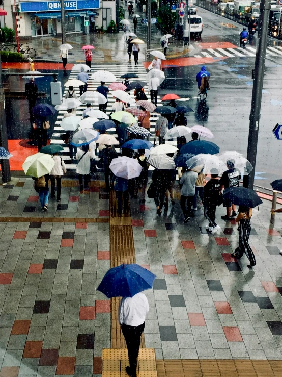 a crowd of people walking down a street while holding umbrellas