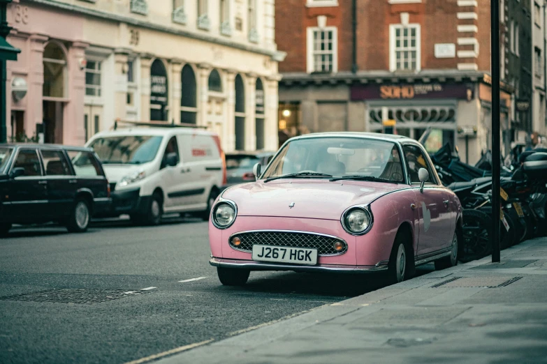 an old pink car on the street near the curb