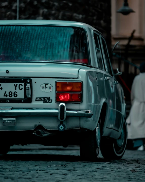 an old grey car parked on the street