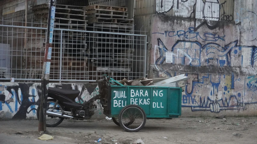 a bike parked next to a garbage container filled with wood