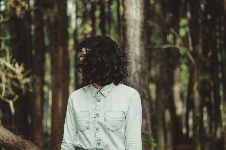 a person wearing a shirt and tie standing in the woods