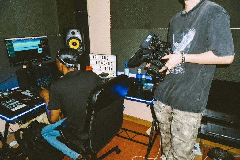 two men standing in a recording studio looking at sound equipment