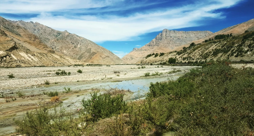 a river and some mountains under a blue sky