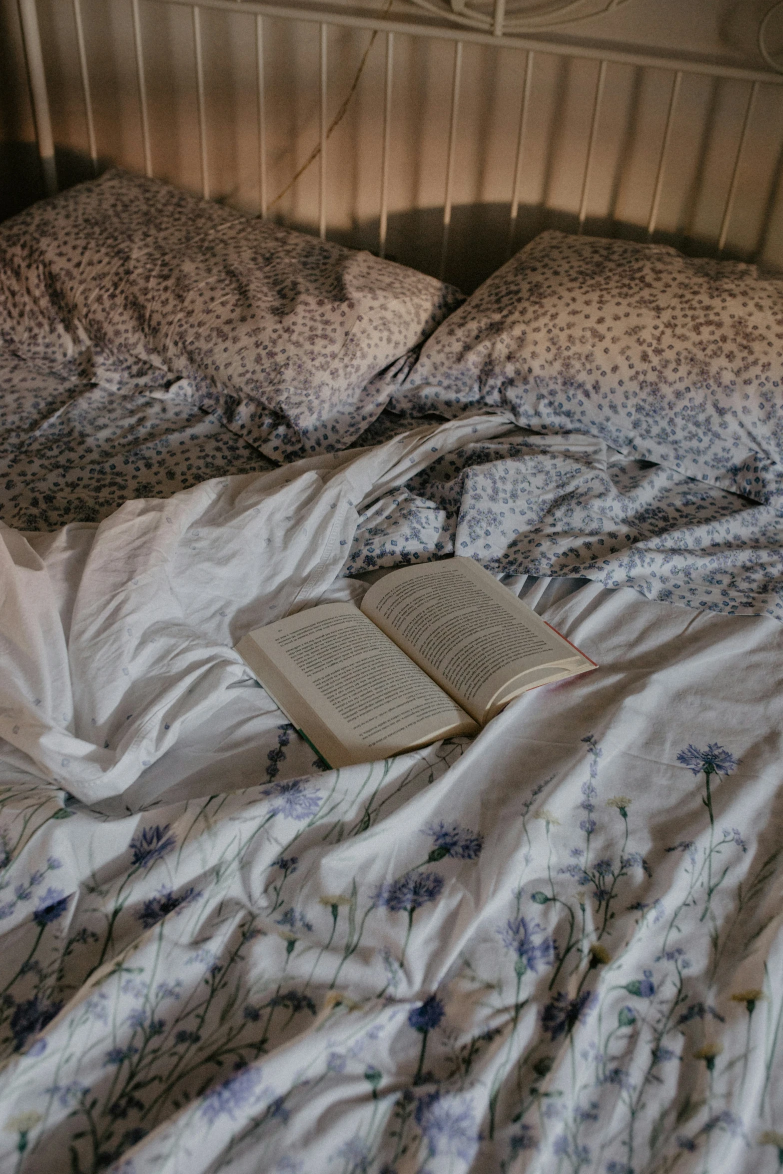 a book sitting on an unmade bed with a pillow