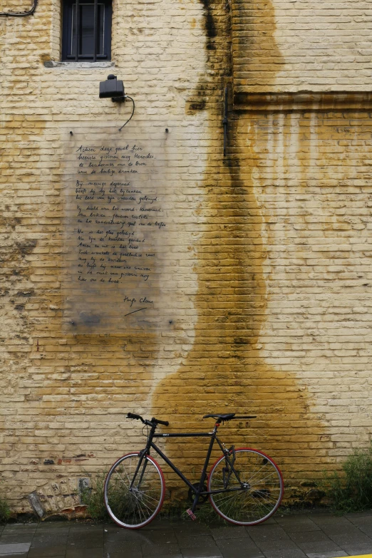 bicycle parked on sidewalk against brick building near pavement