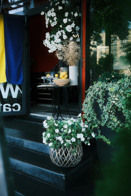 a view of a flower store door with blue awning and a table