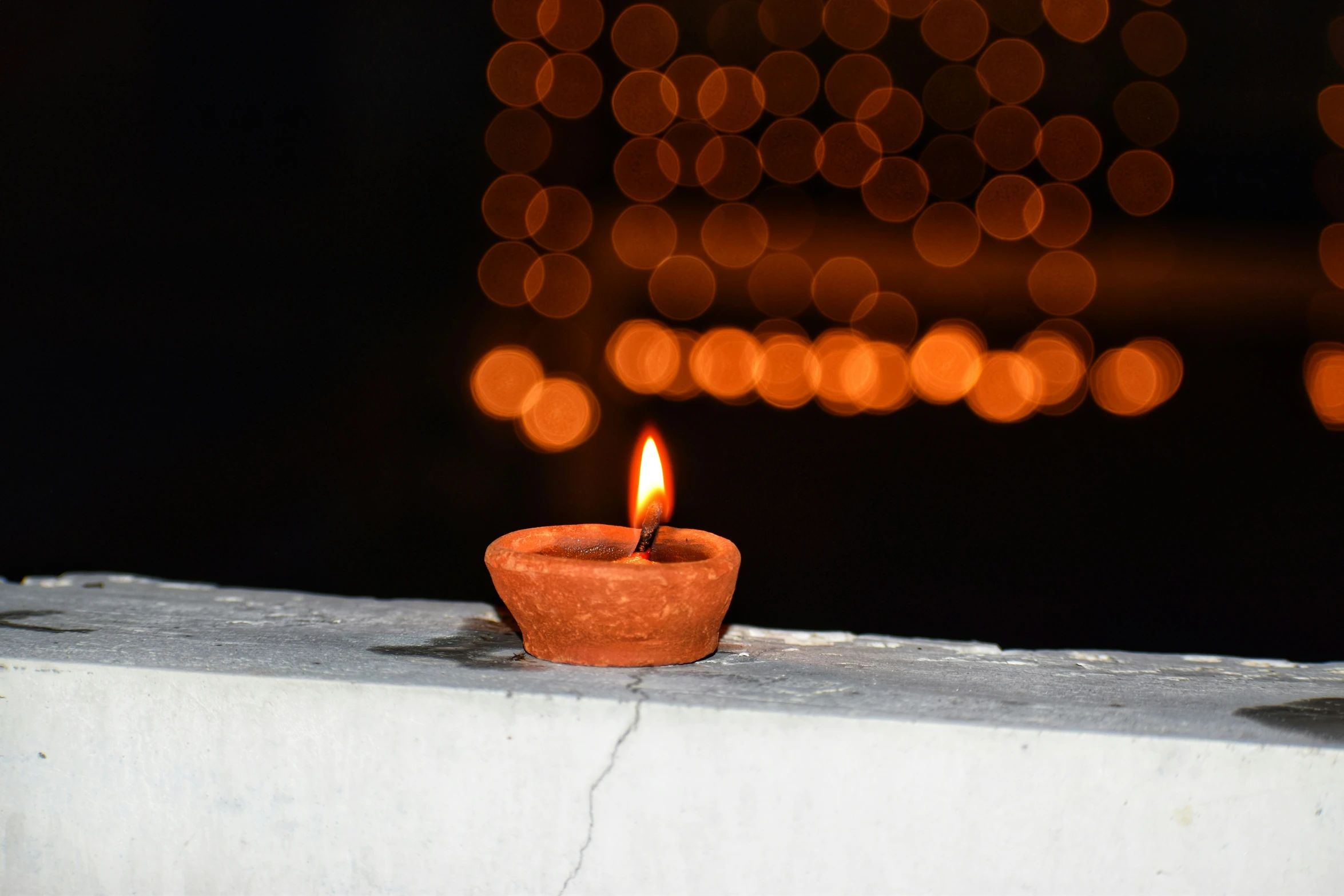 a small ceramic pot that has a candle lit up