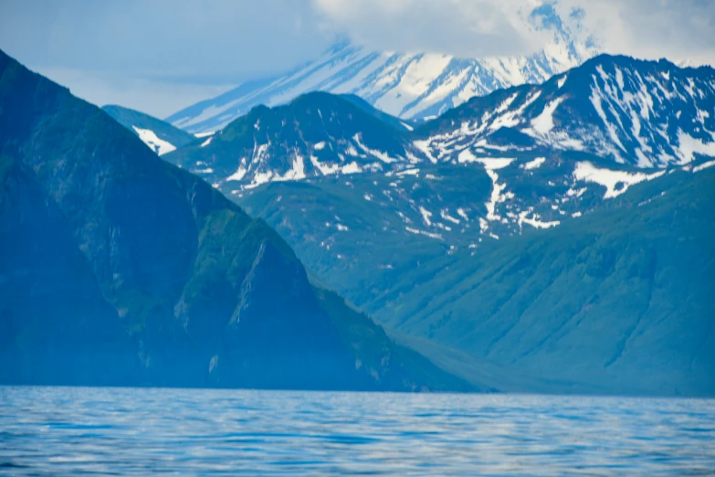 mountains with snow covered peaks sit behind a body of water