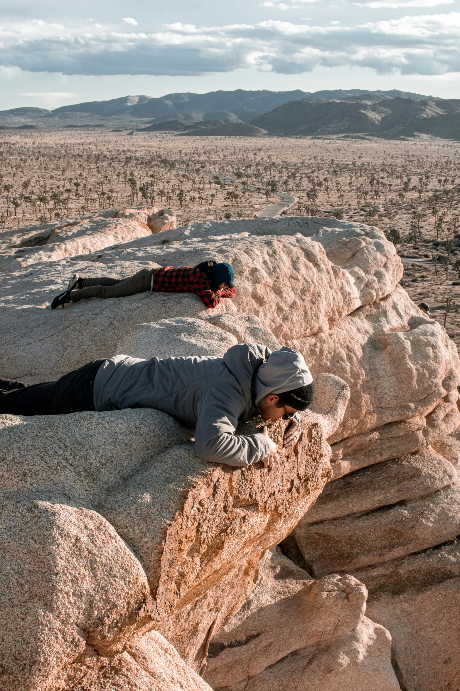 a woman laying on the top of a rock in a desert