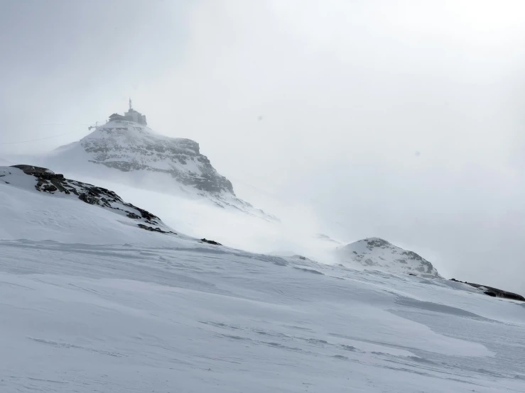 person on skis approaching a ski slope at the bottom of a snowy mountain