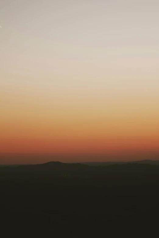 a man holds his surf board as the sun goes down